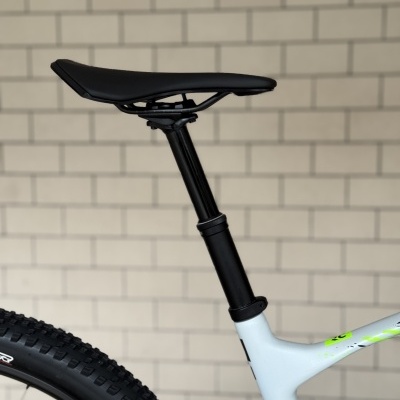 Banco de bicicleta preto e quadro branco com texto Spark RC junto a parede de tijolos