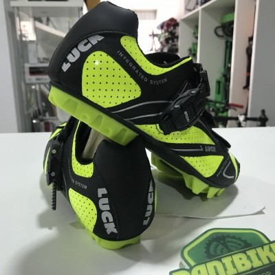 Sapatos de ciclismo pretos e amarelos fluorescentes da marca LUCK numa loja de bicicletas