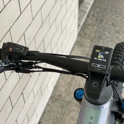 Guiador de bicicleta com visor digital e manípulos pretos em parede com azulejos brancos
