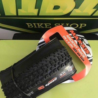 Pneu de bicicleta Maxxis Ardent Race 29x2.20 com detalhes de cravos em fundo verde e amarelo.