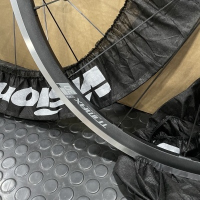 Roda de bicicleta cinza fosco com raios pretos e texto 'TRINX 30T' sobre piso texturizado