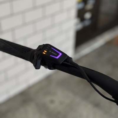 Comando eletrônico preto para bicicleta com luzes coloridas num guiador preto