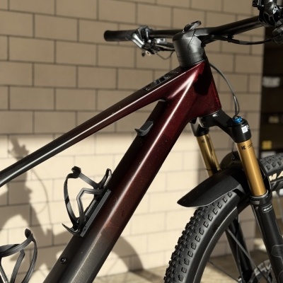 Detalhe da bicicleta de montanha com quadro vermelho e preto e suspensão dianteira dourada