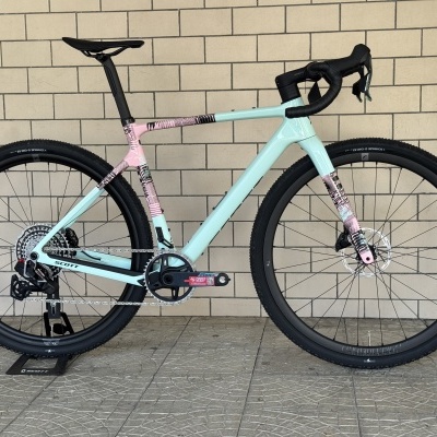 Bicicleta de estrada azul claro e rosa com padrão gráfico preto, pneus Schwalbe, selim e manípulos pretos.