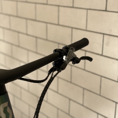 Guiador de bicicleta preta com manete de travão e parede de azulejos brancos ao fundo