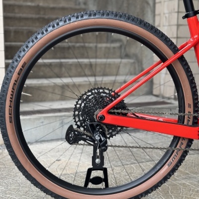 Roda traseira de bicicleta vermelha com pneu Schwalbe SNAKE SKIN castanho e preto em suporte Scott