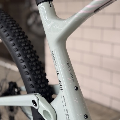 Quadro cinza claro de bicicleta com texto spark 3C, Team Issue e detalhes em rosa.