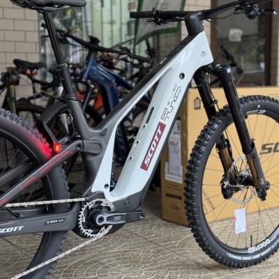Bicicleta elétrica de montanha SCOTT branca e preta em loja com roda traseira com luz vermelha