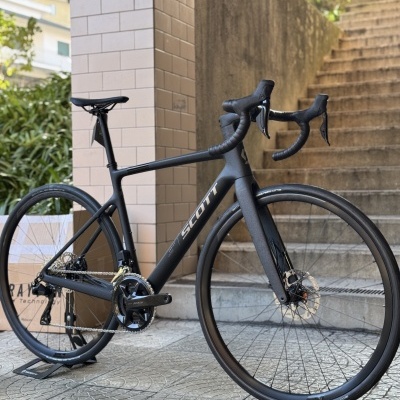 Bicicleta de estrada preta Scott junto a escadas e um pilar