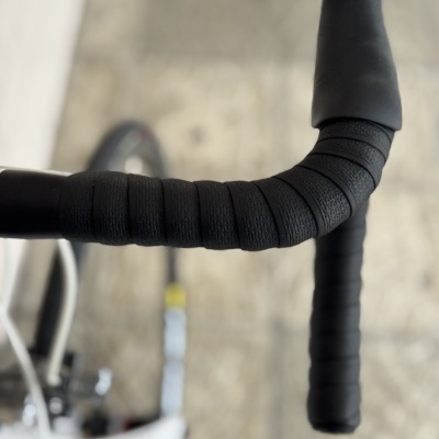 Guiador preto de bicicleta de estrada com fita texturada e punhos na cor preta