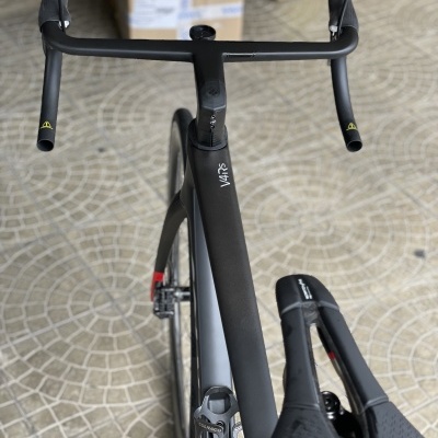 Bicicleta de estrada preta com selim e guiador visíveis sobre mosaico