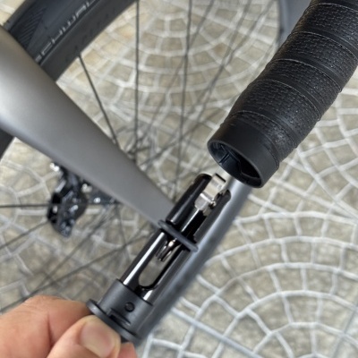 Bicicleta cinzenta com pneu preto Schwalbe e guiador com fita preta junto a componente destacada