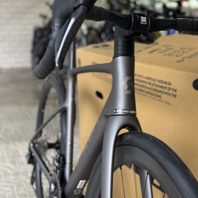 Bicicleta de estrada cinza fosco com detalhes pretos perto de uma caixa de cartão