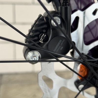 Sistemade travão de disco para bicicleta com pinça Shimano preta e disco de aço ventilado.