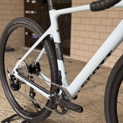 Bicicleta de estrada branca com detalhes a preto, quadro em carbono, pneus Dura-Ace e pedaleira GRX.