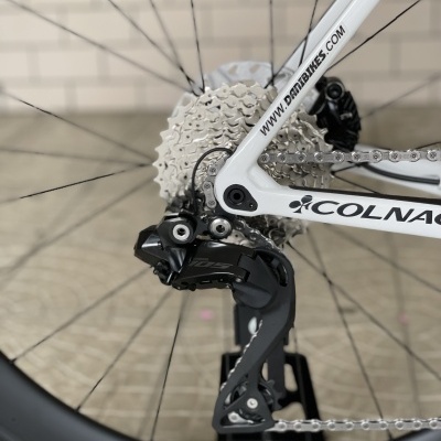 Desviador traseiro e cassete de bicicleta branca com pneus pretos e fundo de azulejos brancos