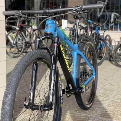 Bicicleta de montanha elétrica azul e preta numa loja com outras bicicletas ao fundo