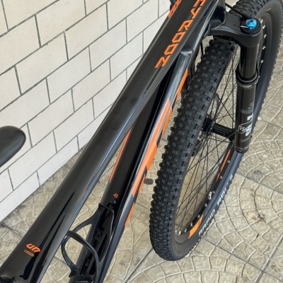 Bicicleta de montanha preta com detalhes laranja e suspensão dianteira azul