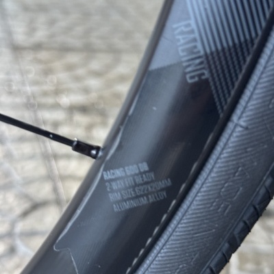 Roda de bicicleta preta com texto no aro e pneu preto com sulcos