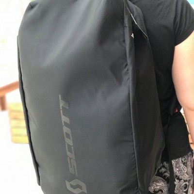Mochila preta rígida com logo SCOTT nas costas de uma pessoa