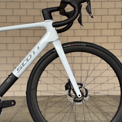 Bicicleta de estrada SCOTT branca e preta com guiador preto e roda dianteira com travão de disco