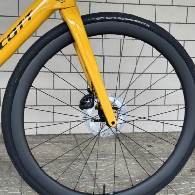 Roda dianteira de bicicleta amarela com pneu preto e parede de azulejos ao fundo