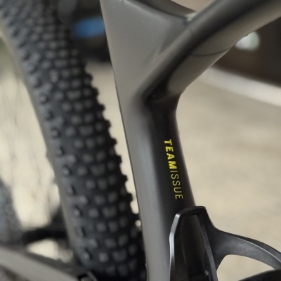 Quadro preto de bicicleta de montanha com pneus cravados e texto amarelo TEAM ISSUE