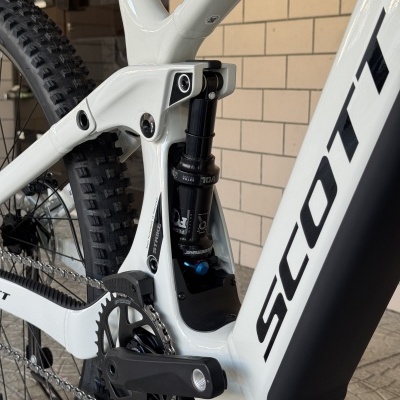 Detalhe de bicicleta branca com suspensão Fox e pneus robustos