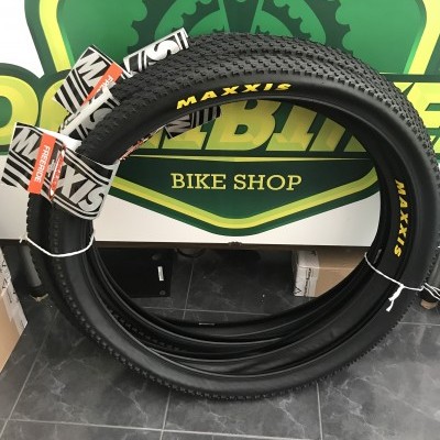 Pneus de bicicleta pretos MAXXIS com letras amarelas em loja com sinalização verde