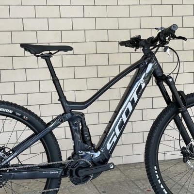 Bicicleta de montanha preta SCOTT junto a parede de blocos bege