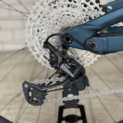 Sistema de transmissão de bicicleta com cassete prateado, desviador XTR preto e quadro azul escuro.