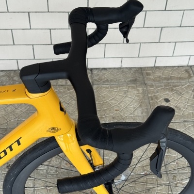 Guidão preto de bicicleta de estrada num quadro amarelo SCOTT com selo DANIBIKES