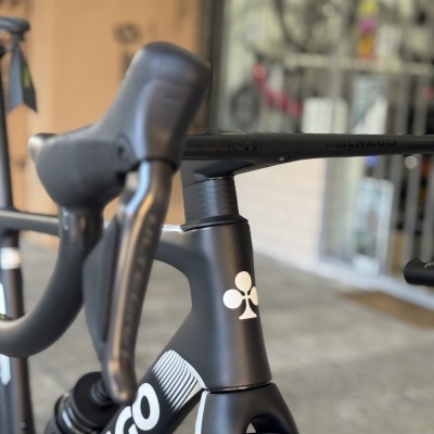 Close-up de bicicleta de estrada preta e branca com logo COLNAGO e pneus Pirelli.