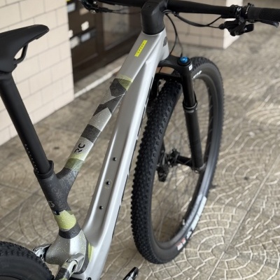 Bicicleta de montanha cinza com detalhes em camuflado e pneus grossos