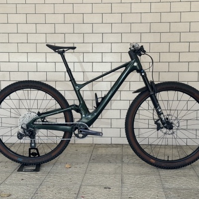 Bicicleta de montanha verde escuro encostada em parede com azulejos brancos