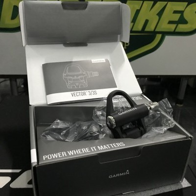 Pedal Garmin Vector 3S numa caixa aberta com manuais e texto na embalagem