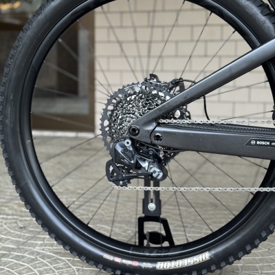 Roda traseira de bicicleta com pneu Maxxis Dissector texto branco e aro preto num suporte Scott