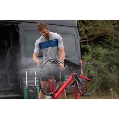 Homem a limpar bicicleta vermelha com equipamento de pressão junto a carrinha preta
