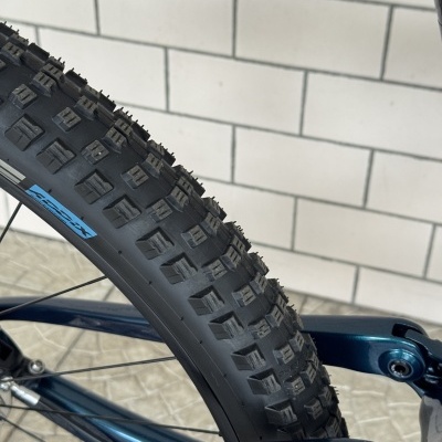 Pneu preto de bicicleta de montanha com textura quadrada sobre quadro azul e parede de azulejos brancos