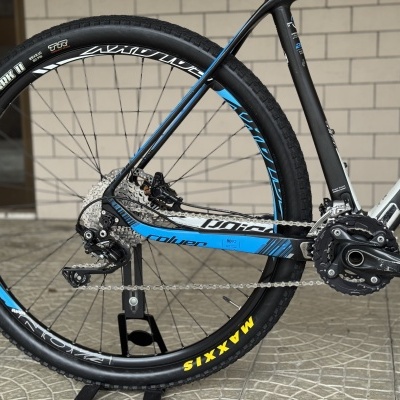 Roda traseira de bicicleta preta e azul com pneu Maxxis e corrente