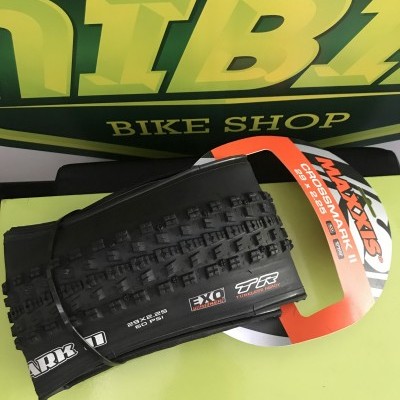 Pneu de bicicleta Maxxis Crossmark II preto com textura off-road em mesa verde