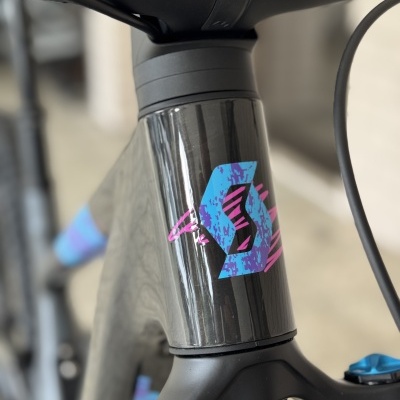 Parte frontal da bicicleta de carbono cinza com detalhes coloridos e etiqueta com letra S