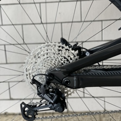 Roda traseira de bicicleta com cassete e câmbio visíveis junto a parede de azulejos brancos