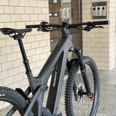 Bicicleta elétrica Scott cinzenta contra parede de azulejos