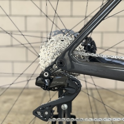 Roda traseira de bicicleta com cassete prateado, desviador Shimano 105 preto e quadro cinza