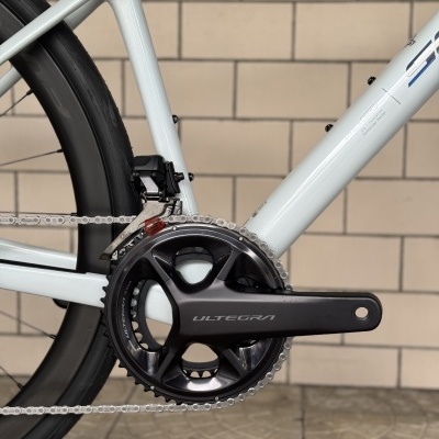 Detalhe da pedaleira e corrente de bicicleta branca com roda preta