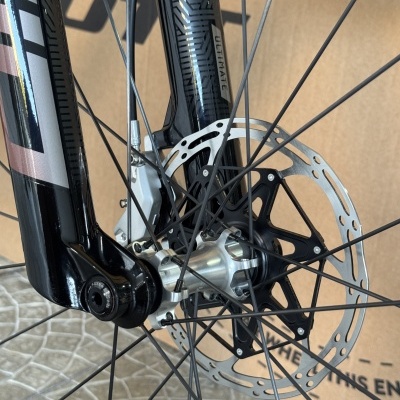 Roda dianteira de bicicleta preta com disco de travão em metal num piso de calçada