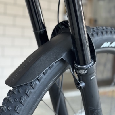 Guarda-lamas preto em suspensão de bicicleta com pneu robusto e texto na suspensão