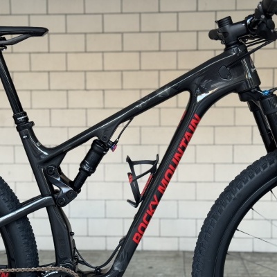 Bicicleta de montanha preta com suspensão completa e texto vermelho ROCKY MOUNTAIN no quadro