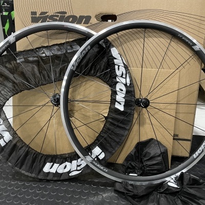 Duas rodas de bicicleta Vision com capas protetoras pretas, diante de caixas de papelão